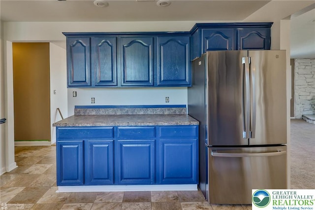 kitchen featuring freestanding refrigerator, dark countertops, and blue cabinetry