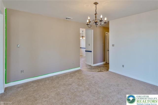 spare room with baseboards, a chandelier, carpet, and visible vents