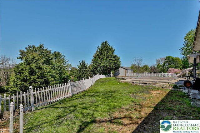 view of yard featuring a storage unit, fence, an outbuilding, and a wooden deck