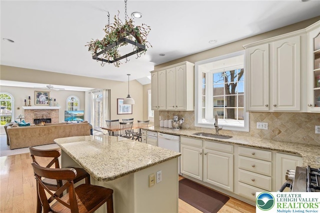 kitchen featuring a sink, a center island, a brick fireplace, and light wood finished floors