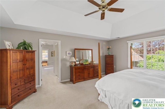 bedroom featuring a ceiling fan, a tray ceiling, light carpet, and baseboards