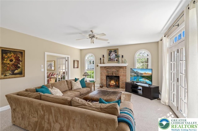carpeted living area featuring a brick fireplace, ceiling fan, and baseboards