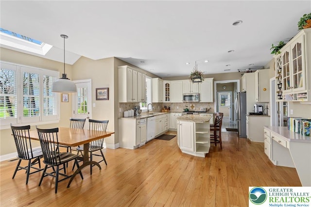 kitchen with light wood-style floors, a center island, white cabinets, tasteful backsplash, and stainless steel appliances