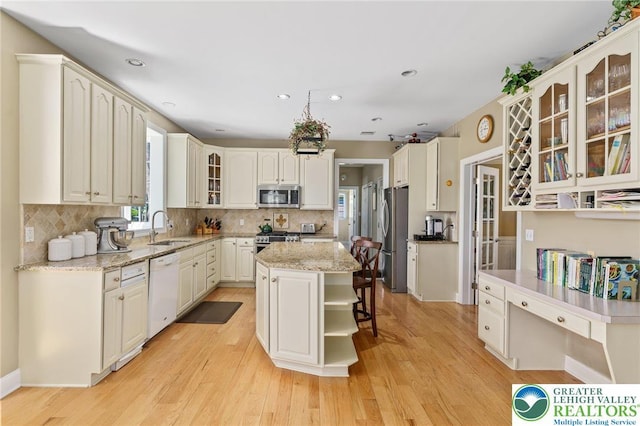 kitchen with appliances with stainless steel finishes, tasteful backsplash, a kitchen island, and light wood-type flooring