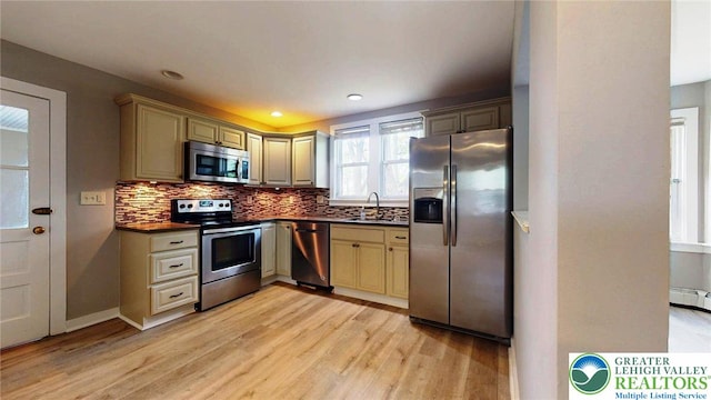 kitchen with stainless steel appliances, dark countertops, a sink, and light wood-style floors