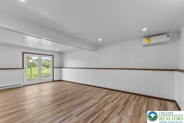 empty room featuring a baseboard radiator, a wall mounted AC, recessed lighting, and wood finished floors