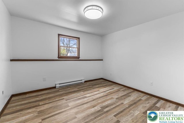 spare room featuring baseboards, baseboard heating, and wood finished floors