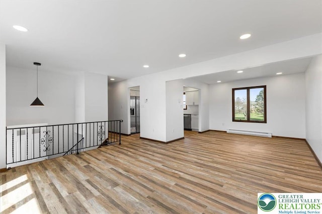 interior space featuring recessed lighting, baseboards, a baseboard heating unit, and wood finished floors