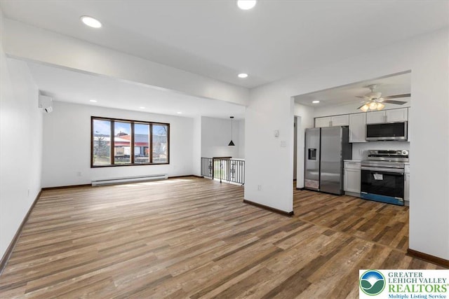 unfurnished living room with ceiling fan, baseboard heating, wood finished floors, baseboards, and recessed lighting