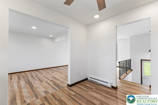 empty room featuring wood finished floors, baseboards, ceiling fan, recessed lighting, and a baseboard radiator