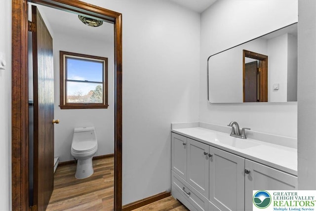 bathroom featuring vanity, baseboards, toilet, and wood finished floors