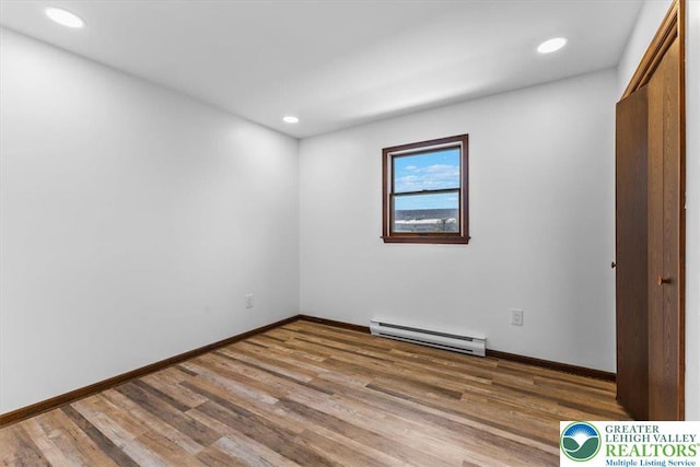 unfurnished bedroom featuring recessed lighting, baseboards, a baseboard heating unit, and wood finished floors
