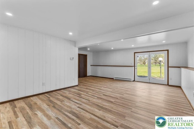 unfurnished living room with wood finished floors, recessed lighting, a decorative wall, and a baseboard heating unit