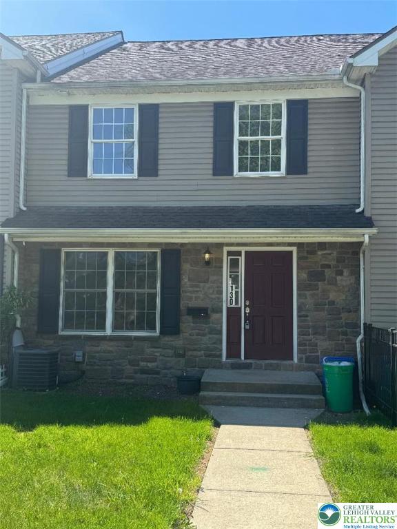 traditional-style home with a front lawn, central AC, and stone siding