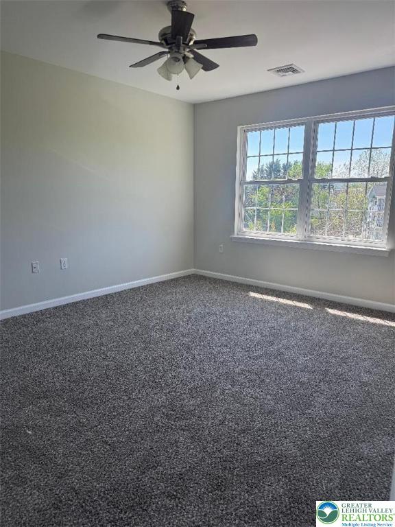 carpeted empty room with ceiling fan, visible vents, and baseboards