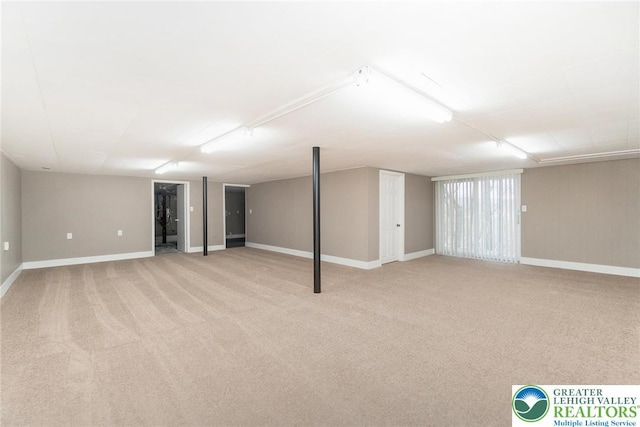 finished below grade area featuring baseboards and light carpet