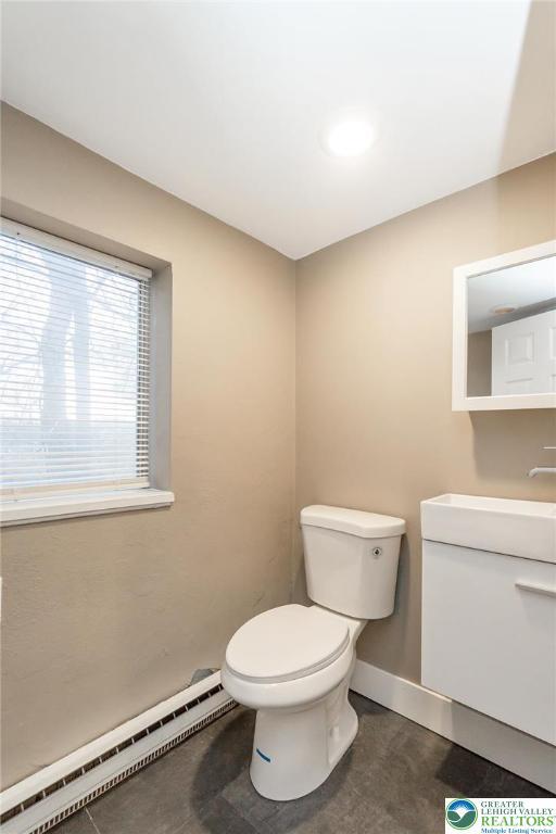 bathroom featuring baseboards, a baseboard radiator, vanity, and toilet