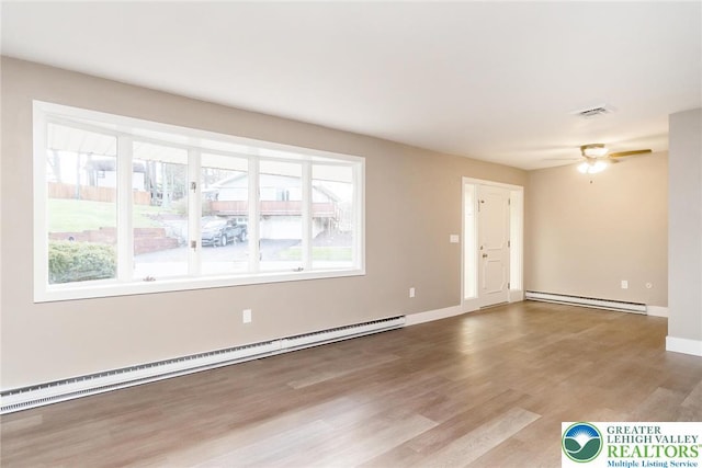 unfurnished living room with wood finished floors, a healthy amount of sunlight, and a baseboard radiator