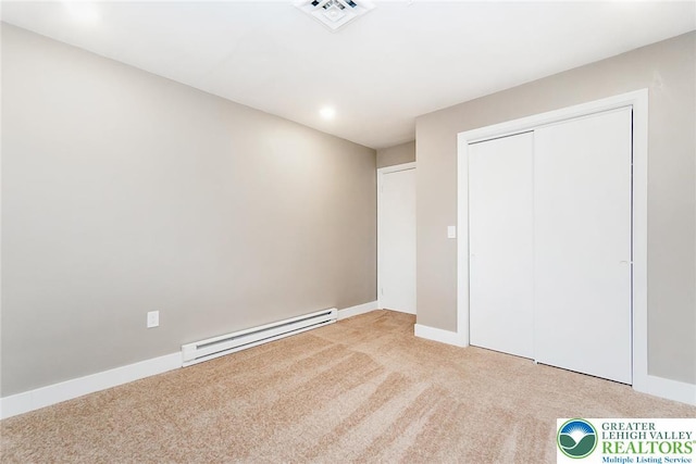 unfurnished bedroom with visible vents, a closet, baseboards, a baseboard heating unit, and carpet flooring