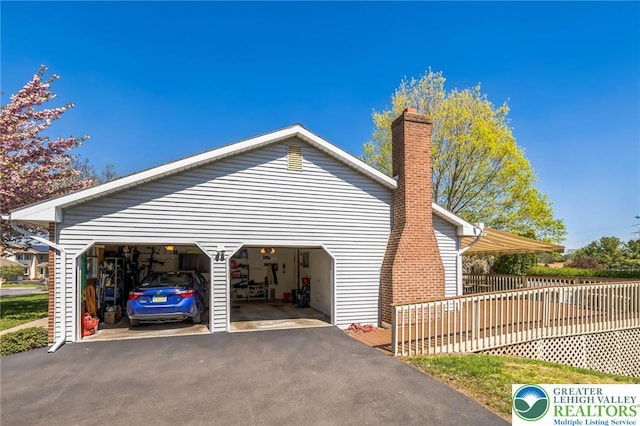 exterior space featuring fence, a chimney, and a garage