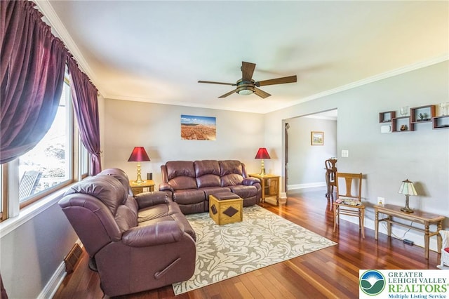 living area with crown molding, a ceiling fan, baseboards, and wood finished floors