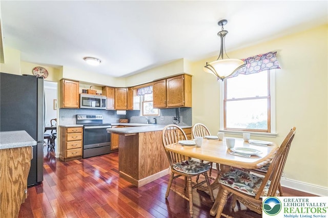 kitchen featuring light countertops, stainless steel appliances, dark wood-style floors, and a peninsula