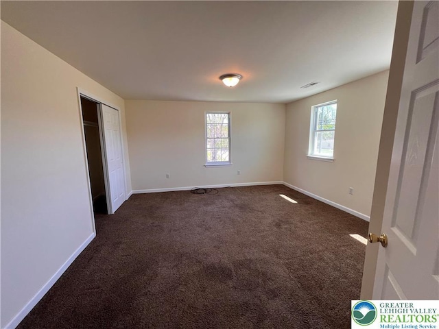 unfurnished bedroom featuring baseboards, visible vents, and dark colored carpet