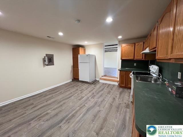 kitchen with freestanding refrigerator, baseboards, recessed lighting, under cabinet range hood, and light wood finished floors