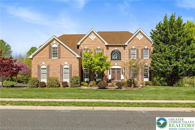 colonial home featuring brick siding and a front yard