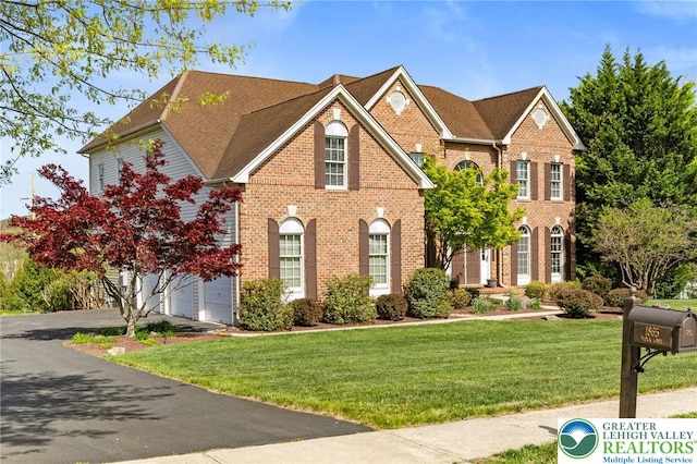 view of front of property featuring driveway, a front lawn, and brick siding