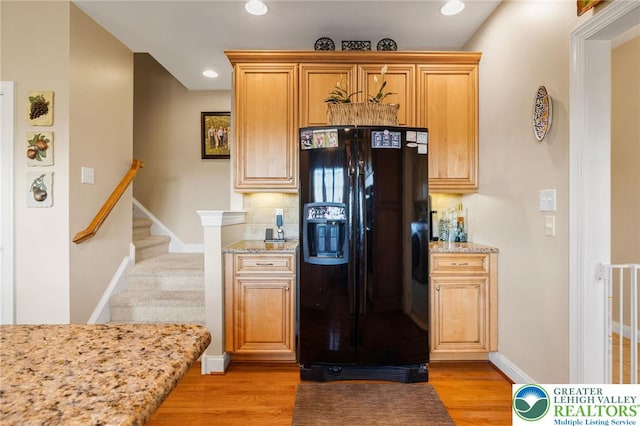 kitchen featuring baseboards, tasteful backsplash, black fridge, and light stone counters