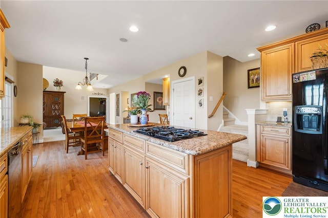 kitchen with light stone countertops, light wood finished floors, and black appliances