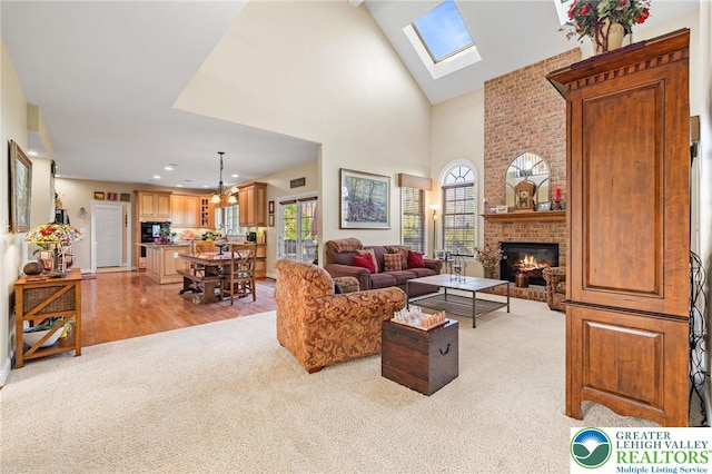 living area featuring light carpet, a brick fireplace, high vaulted ceiling, recessed lighting, and a skylight