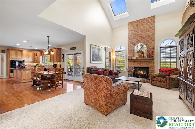 living area featuring a brick fireplace, light wood-type flooring, a wealth of natural light, and a towering ceiling