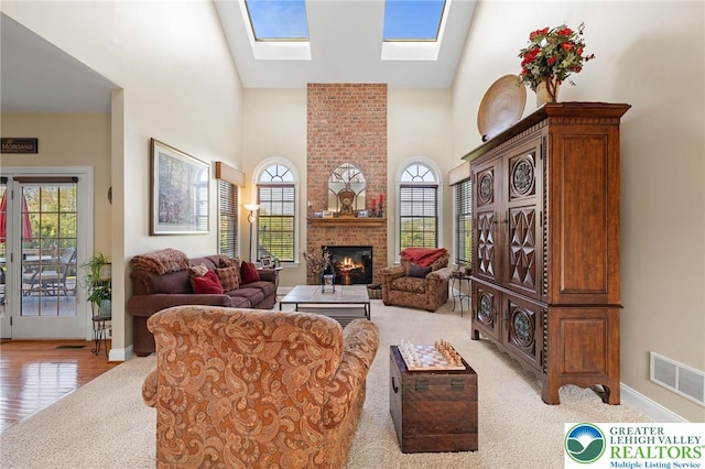 living area with high vaulted ceiling, a wealth of natural light, a fireplace, and visible vents