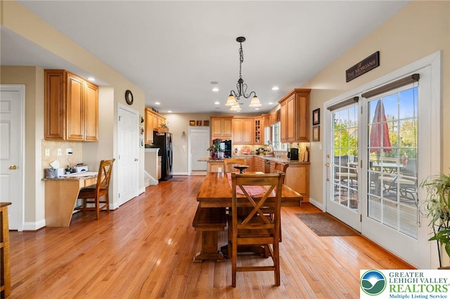 dining room with an inviting chandelier, light wood-style flooring, and baseboards