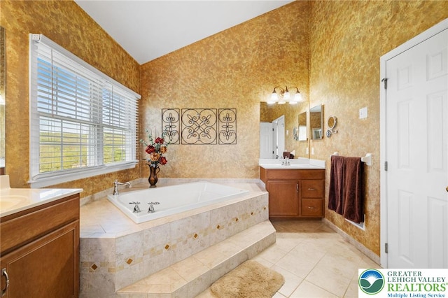 full bath featuring a bath, a sink, two vanities, and tile patterned floors