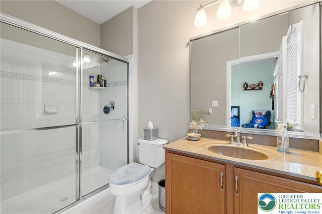bathroom featuring toilet, a shower stall, and vanity
