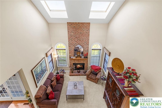 living room with carpet flooring, a fireplace, a high ceiling, and a skylight