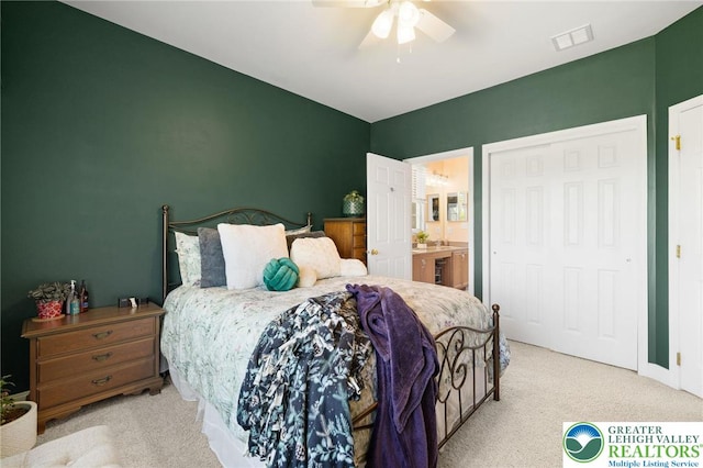 carpeted bedroom with connected bathroom, ceiling fan, and visible vents