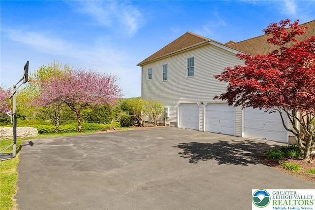 view of property exterior featuring a garage, driveway, and a shingled roof