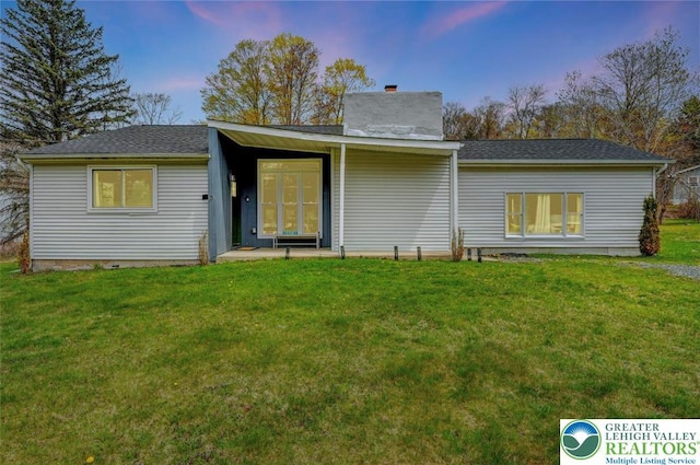 134 Altemose Rd, Tobyhanna Twp, PA 18347 - back of house at dusk featuring a shingled roof, a yard, and a chimney
