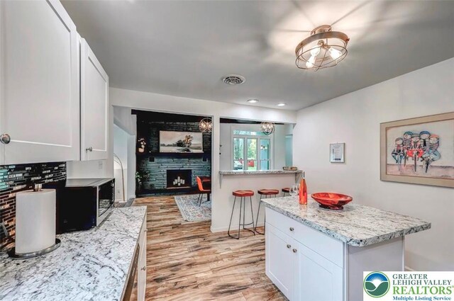 134 Altemose Rd, Tobyhanna Twp, PA 18347 - kitchen with light wood-style floors, a fireplace, stainless steel microwave, and white cabinetry