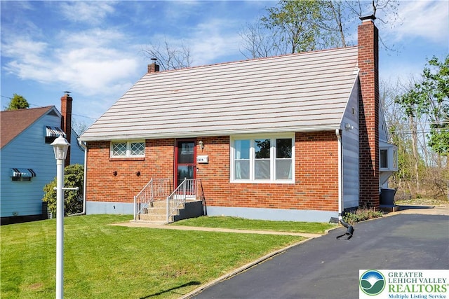 view of front facade with a chimney, a front lawn, and brick siding