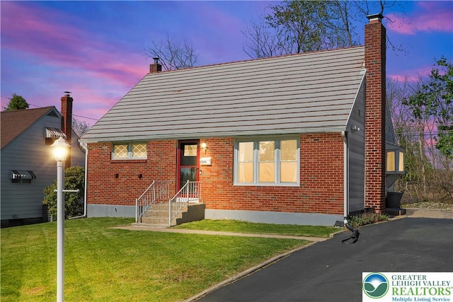 bungalow-style house with brick siding, a front yard, and a chimney