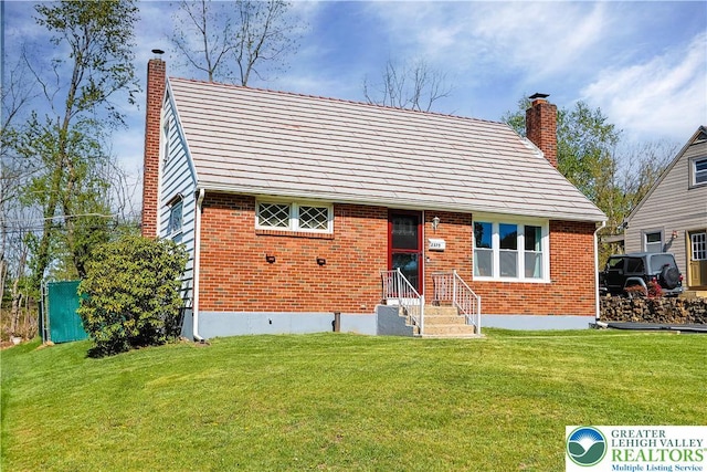 view of front of house featuring brick siding, a chimney, and a front yard