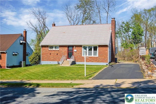 bungalow-style house featuring a chimney, brick siding, central AC, aphalt driveway, and a front lawn