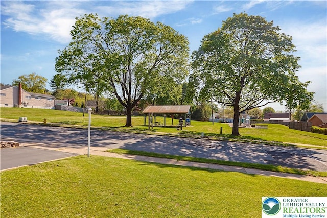 view of property's community featuring a lawn, fence, and a gazebo