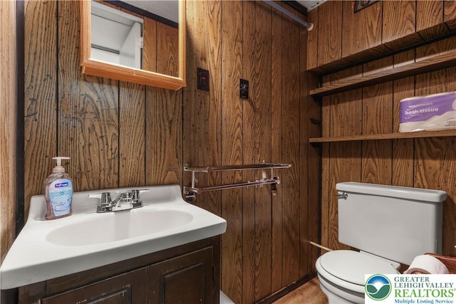bathroom with toilet, wood walls, and vanity