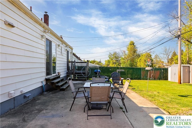 view of patio featuring outdoor dining space, an outbuilding, a shed, and a fenced backyard